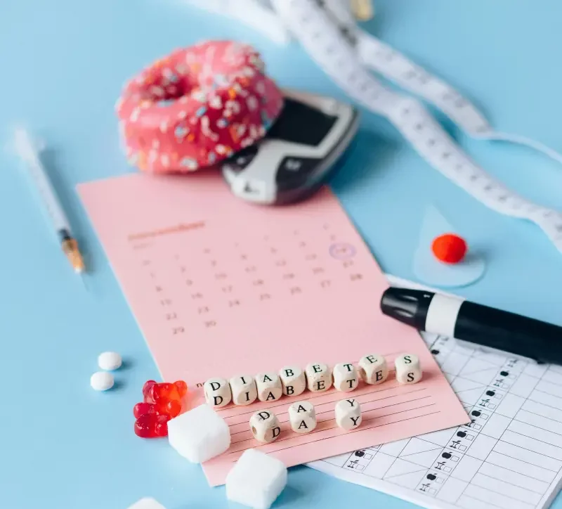 Glukometr, strzykawka i kostki cukru obok kalendarza z hasłem diabetes day